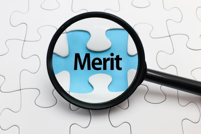 拡大鏡で“Merit”と書かれたパズルのピースを強調している画像

